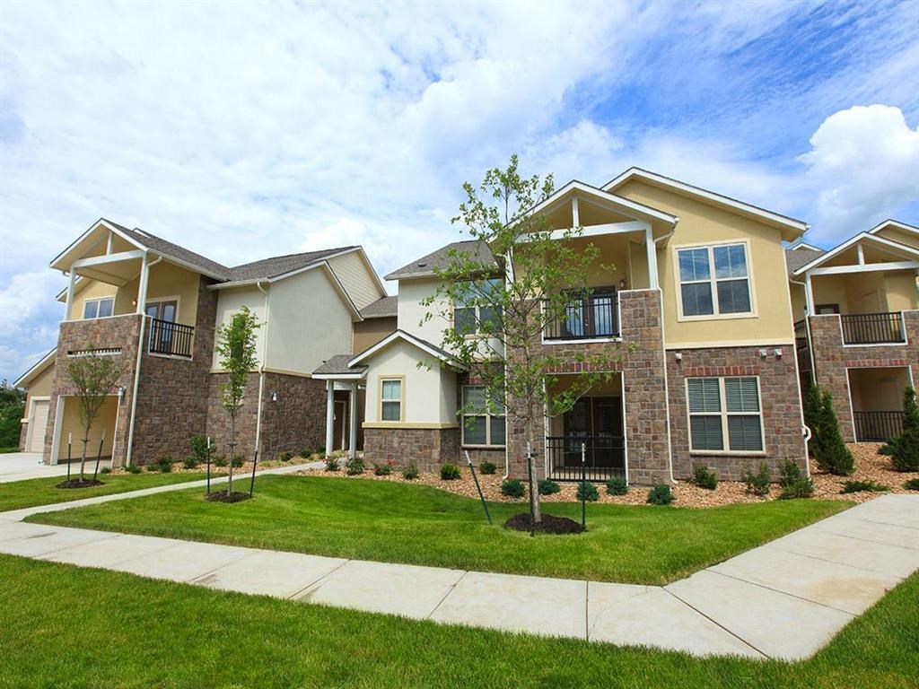 an exterior view of an apartment building with grass and trees