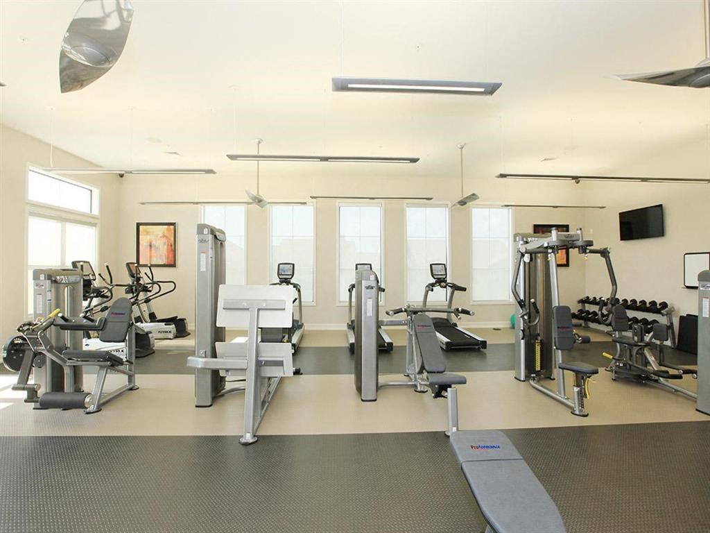 a gym with weights and cardio equipment in a room with windows