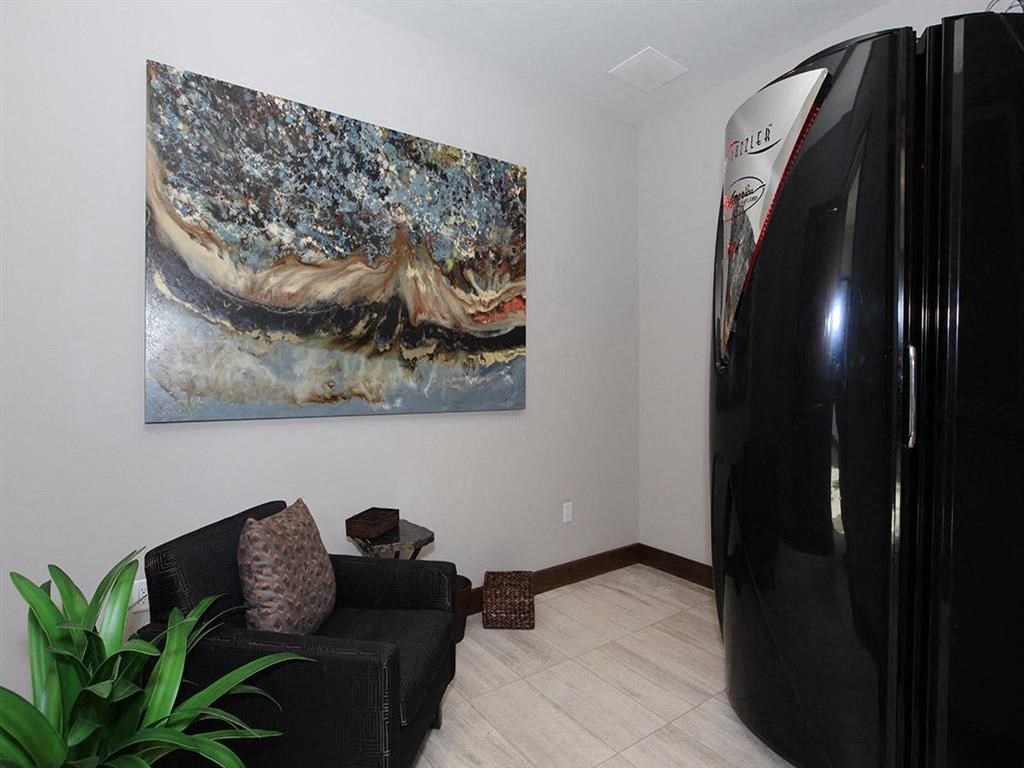 a living room with a black refrigerator and a painting on the wall