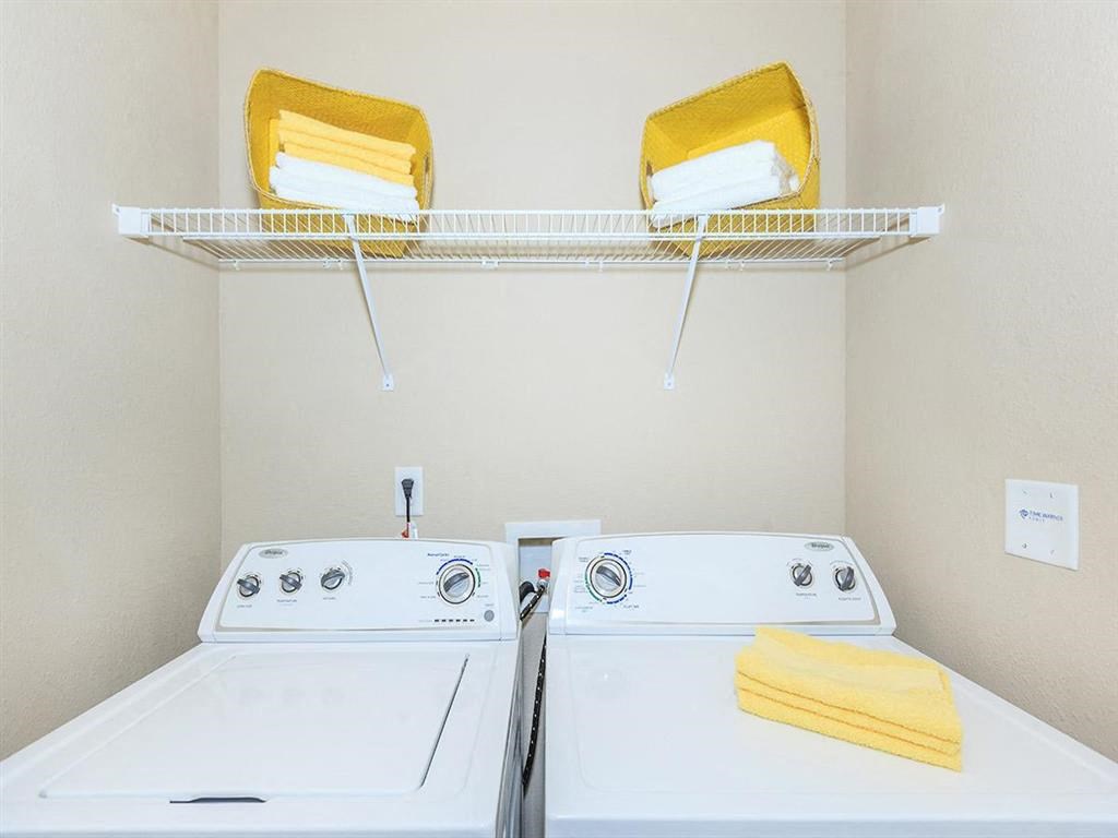 two washers and a dryer in a laundry room with a rack