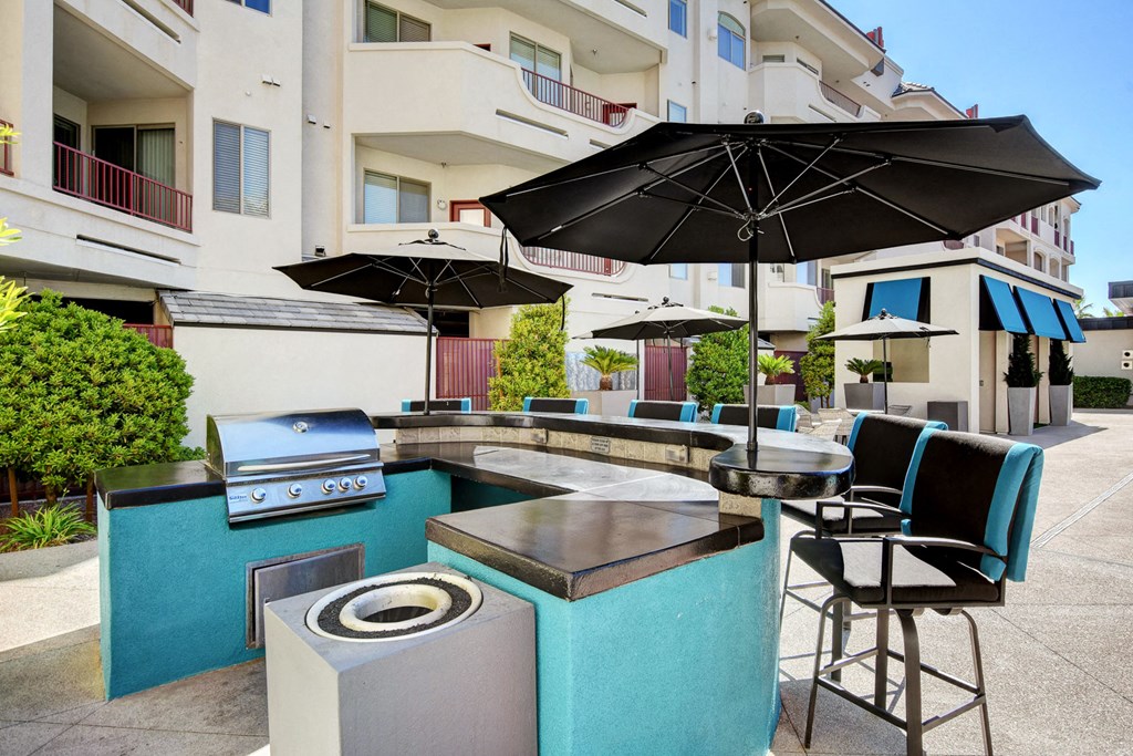 a patio with a grill and tables with umbrellas