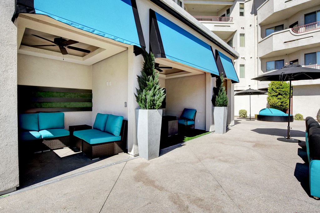 a patio with blue chairs and umbrellas in front of a building