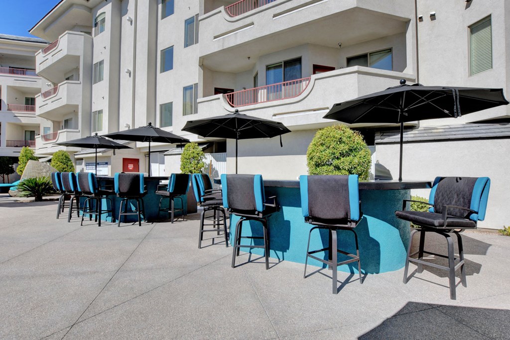 a patio with tables and chairs and umbrellas in front of a building