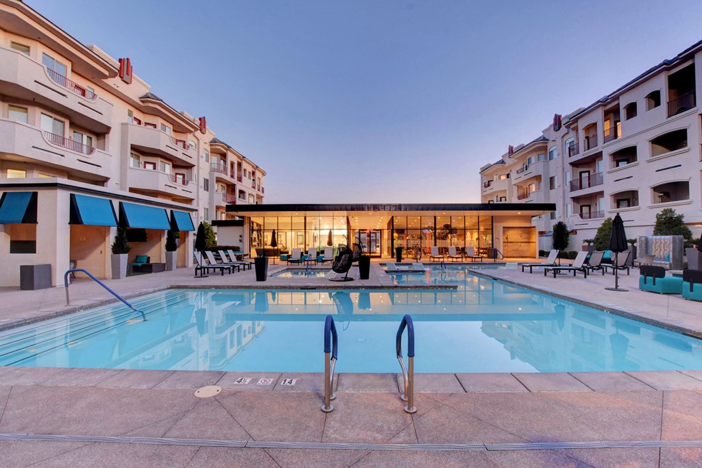 a swimming pool at night next to an apartment building
