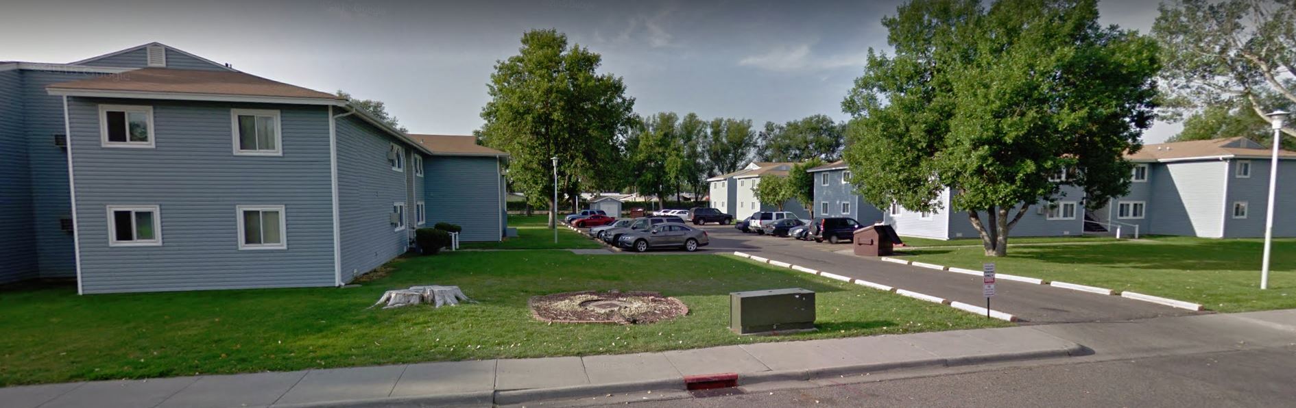 an image of a neighborhood with houses and cars parked in the grass