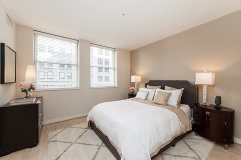 a bedroom with a large bed and two windows