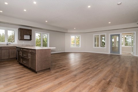 the kitchen and living room of a new home with wood flooring