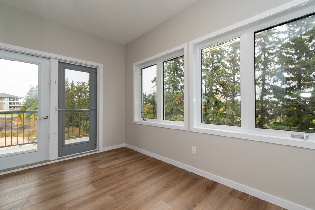 an empty living room with windows and a door to a balcony