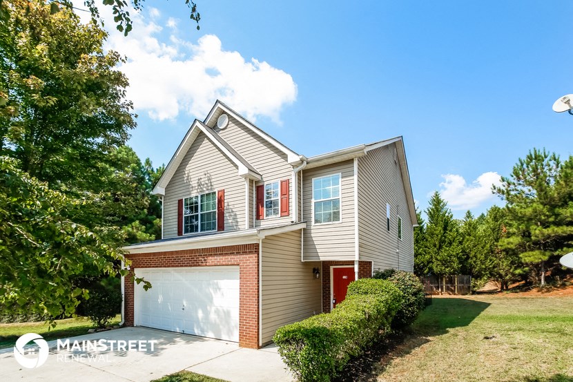 a beige house with a garage with a red door