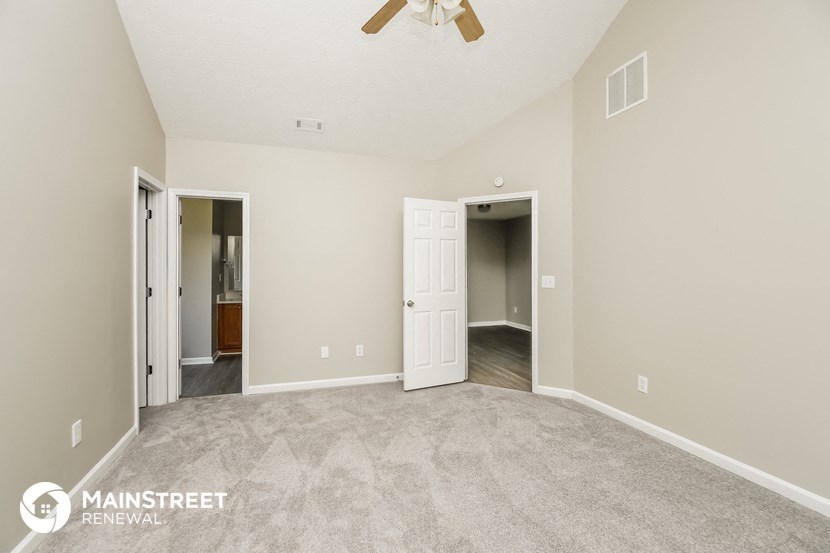 a spacious living room with carpet and a ceiling fan