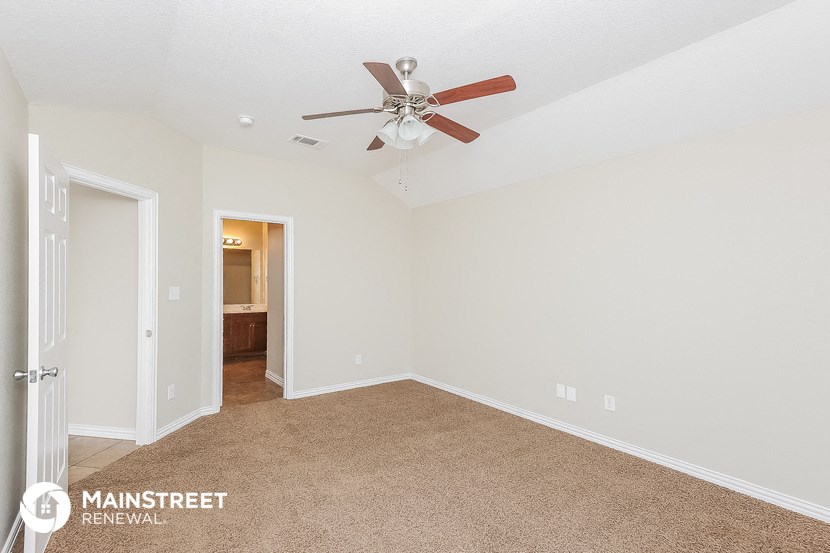 the master bedroom has a ceiling fan and carpeted flooring