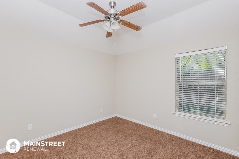 the master bedroom has a ceiling fan and a window