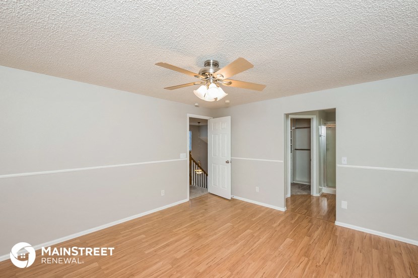 an empty living room with a ceiling fan and wood flooring