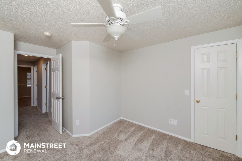 the living room of an apartment with a ceiling fan