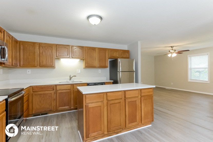 an empty kitchen with wooden cabinets and a white counter top