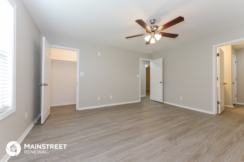 a spacious living room with wood flooring and a ceiling fan
