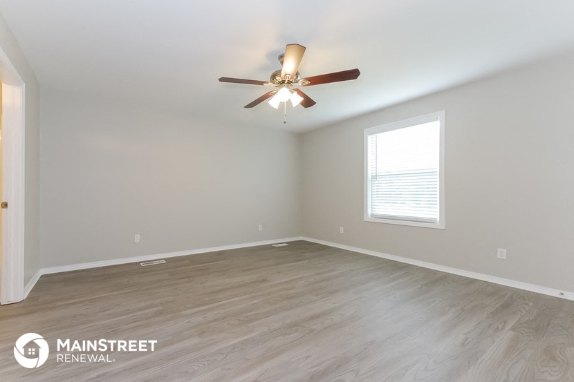 the spacious living room with wood flooring and a ceiling fan