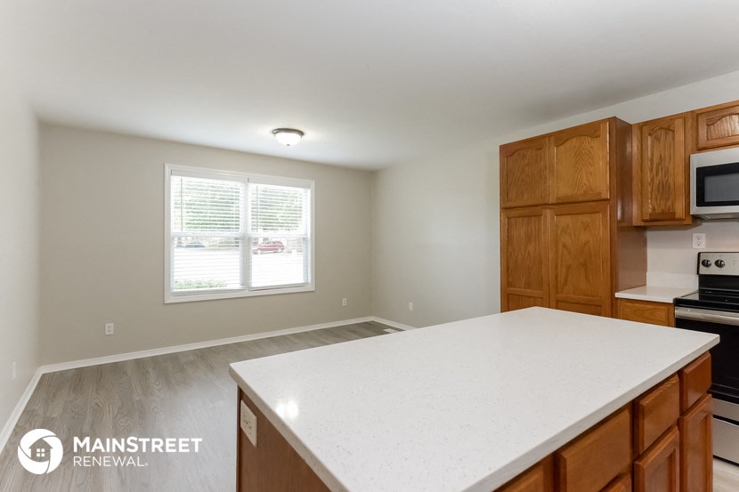 a kitchen with a white counter top and wooden cabinets