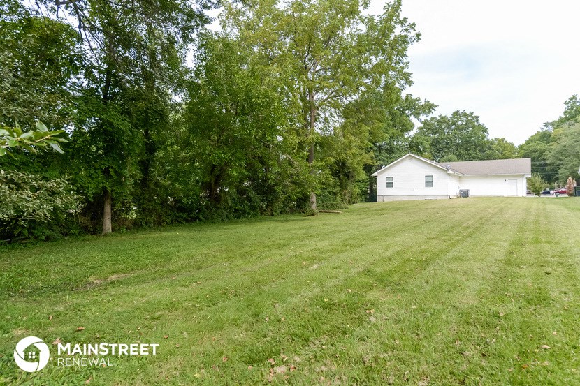 a large yard with a white house and trees