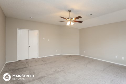 the spacious living room with carpet and ceiling fan