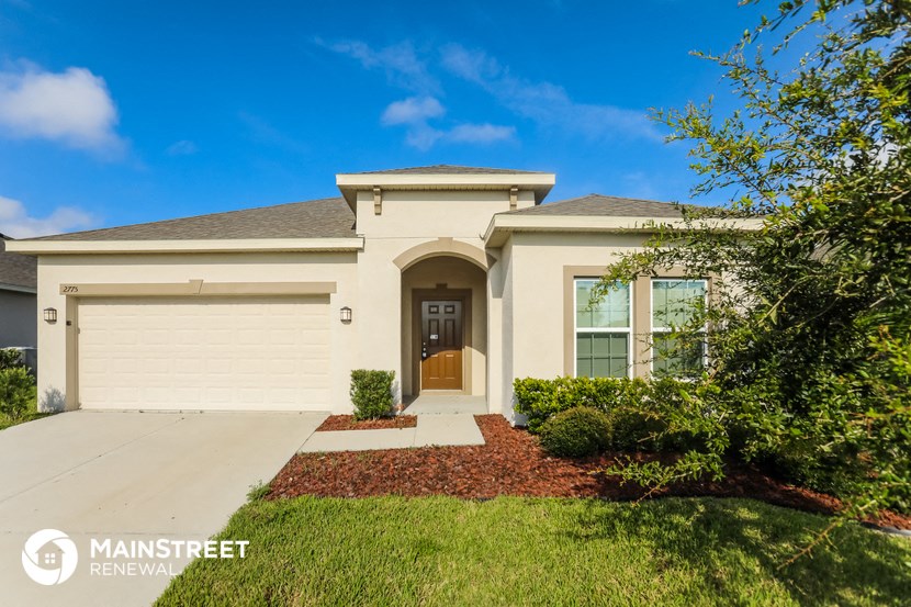 a beige house with a garage door and a lawn