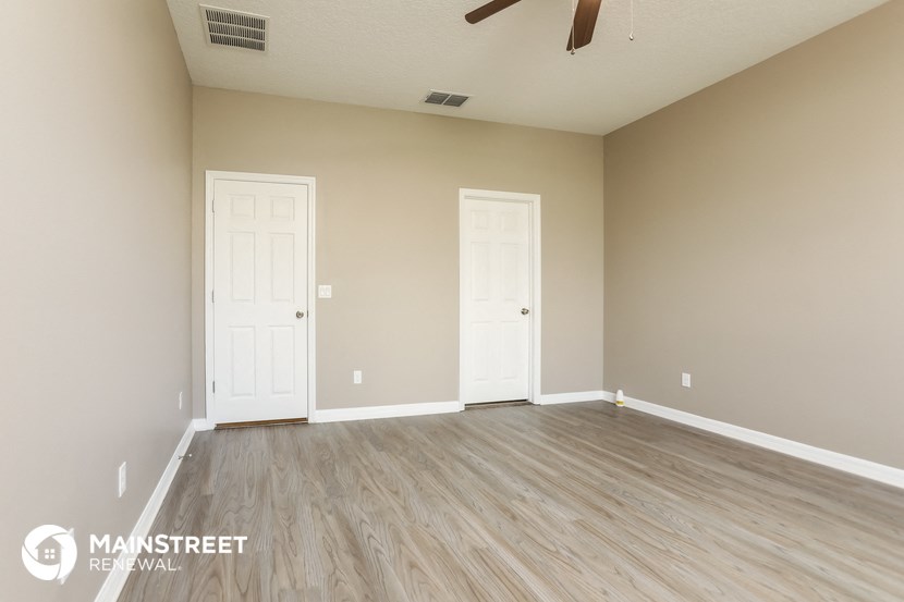an empty room with two doors and a ceiling fan