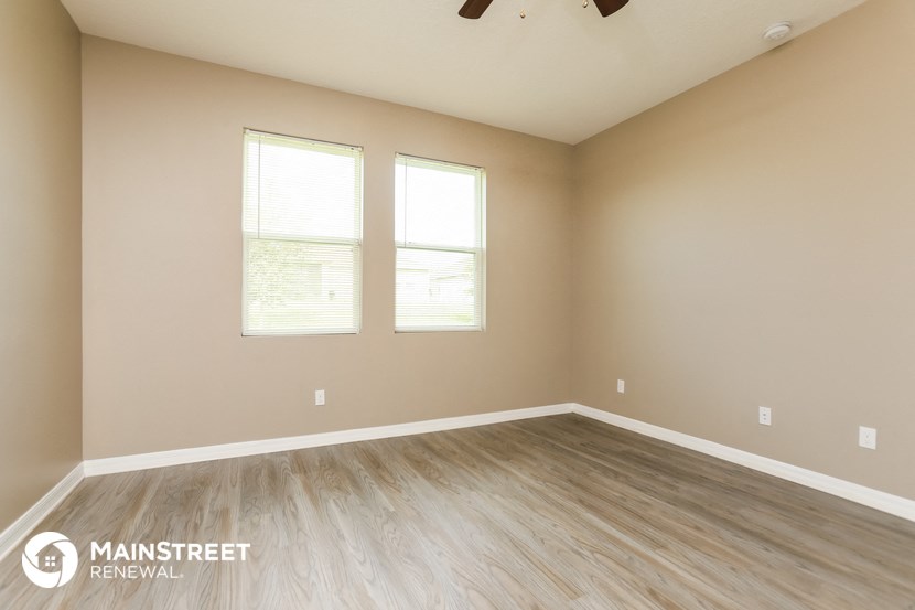 the spacious living room with wood flooring and two windows
