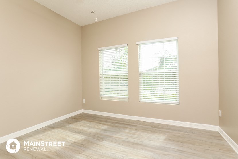 an empty room with a wood floor and two windows