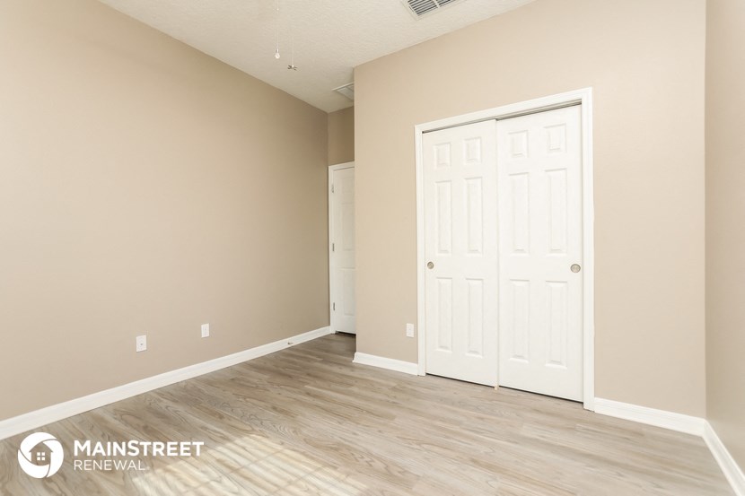 the living room of a new home with a white door and wood flooring