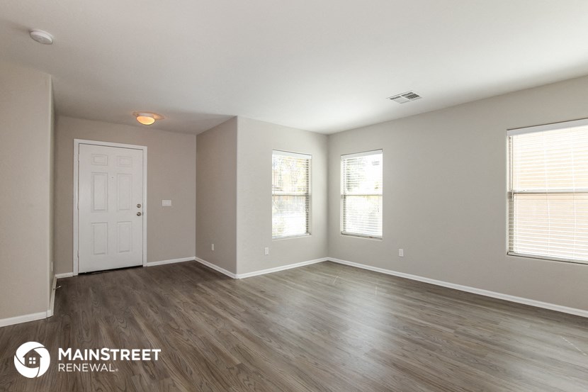 the spacious living room with wood flooring and a white door