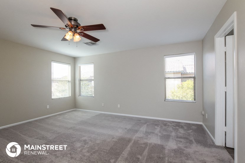 the spacious living room with ceiling fan and windows