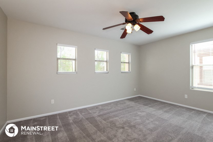 the spacious living room with carpeting and a ceiling fan