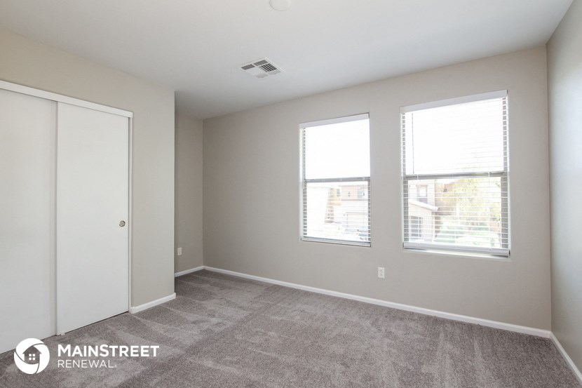 the living room of an apartment with two windows and a closet