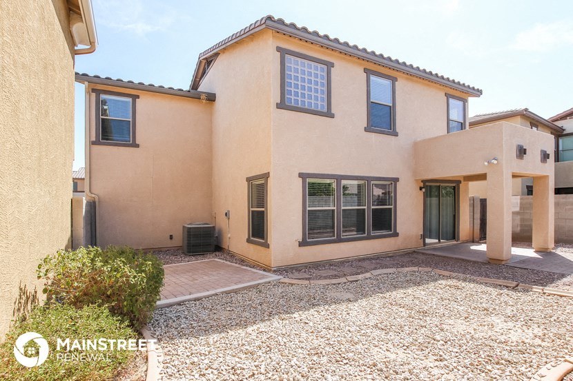 a beige house with a gravel yard and a driveway