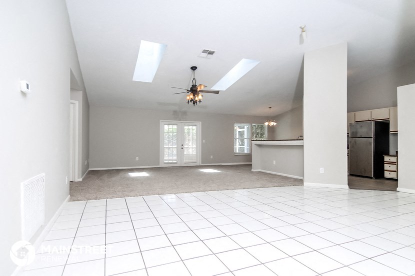 an empty living room with a white tile floor and a ceiling fan