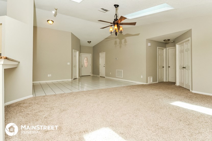 an empty living room with a ceiling fan
