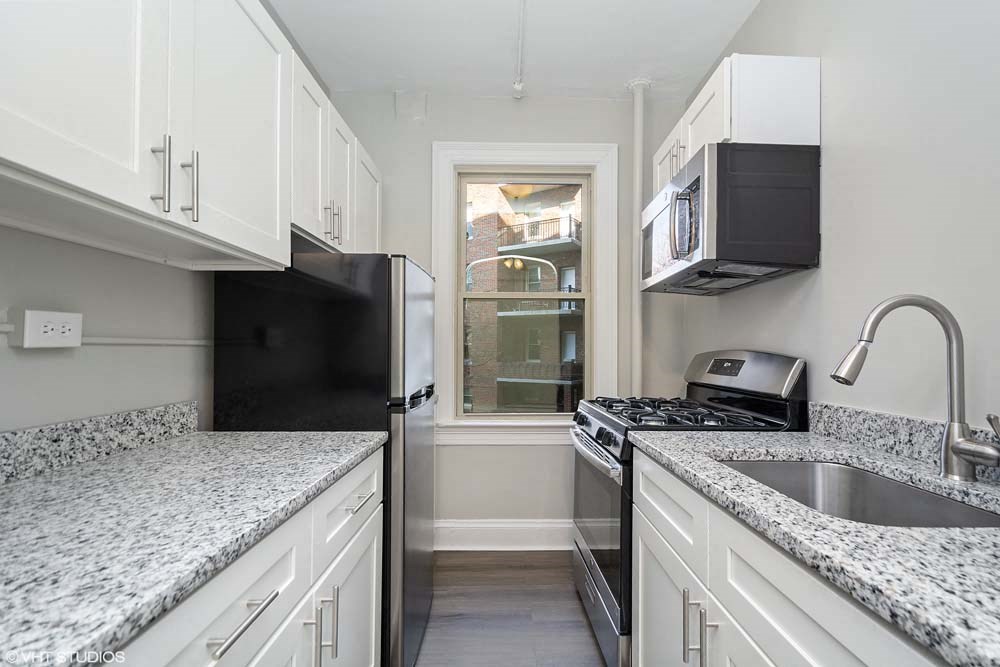 a kitchen with white cabinets and a window