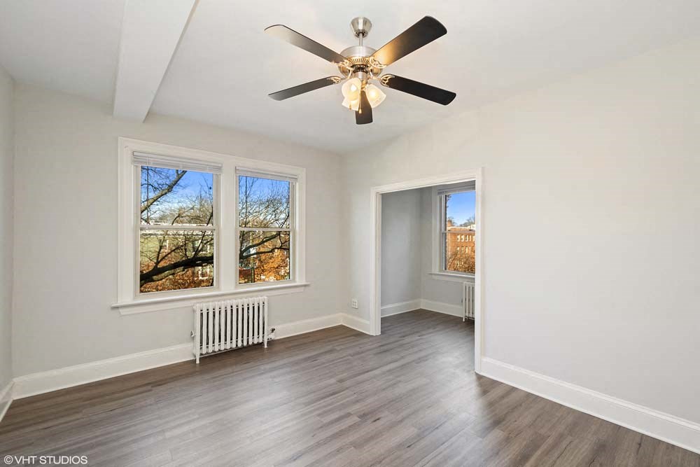 an empty bedroom with a ceiling fan and three windows
