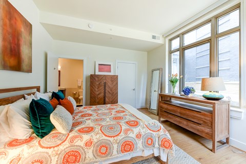 a bedroom with a bed and a dresser and large windows