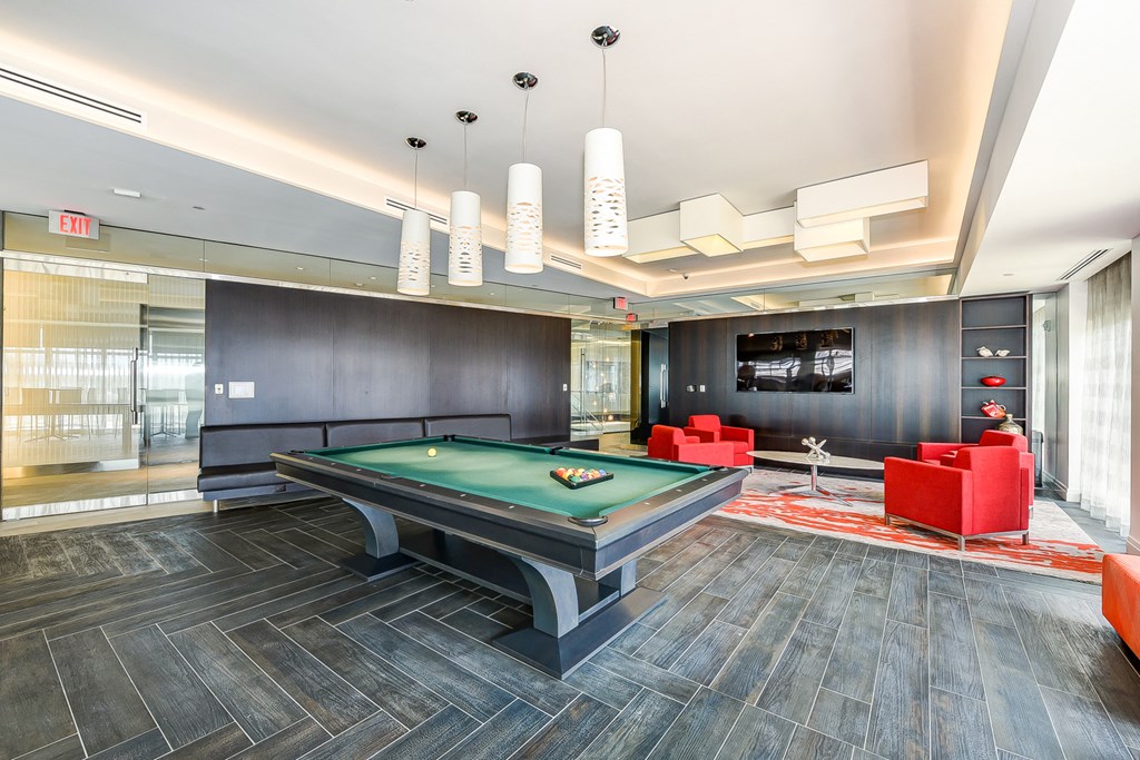 a game room with a pool table and red chairs
