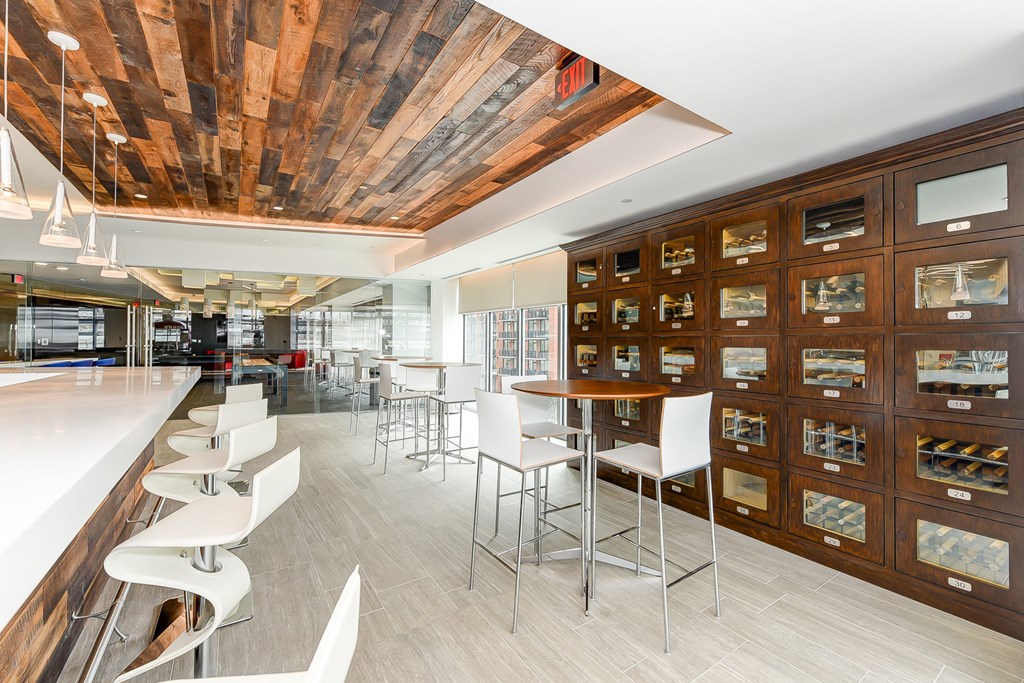 a tasting room with white chairs and a bar with wooden cabinets
