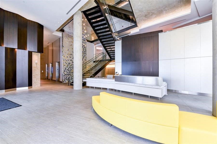 a large lobby with a yellow couch and a staircase