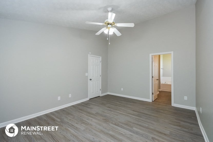 the living room of an apartment with gray walls and a ceiling fan