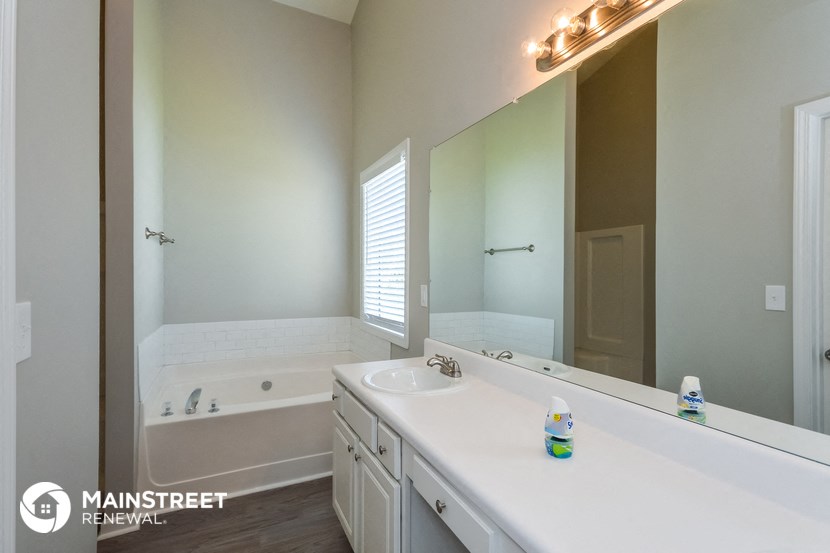 a bathroom with a large mirror and a tub and sink
