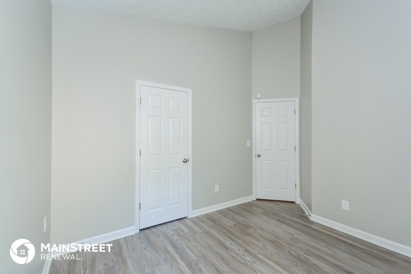 a bedroom with two white doors and a wood floor