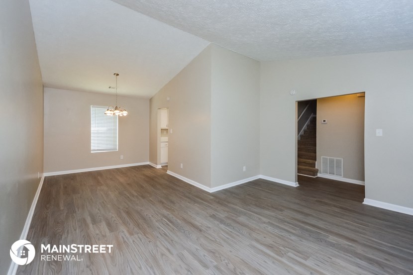 a spacious living room with wood flooring and white walls