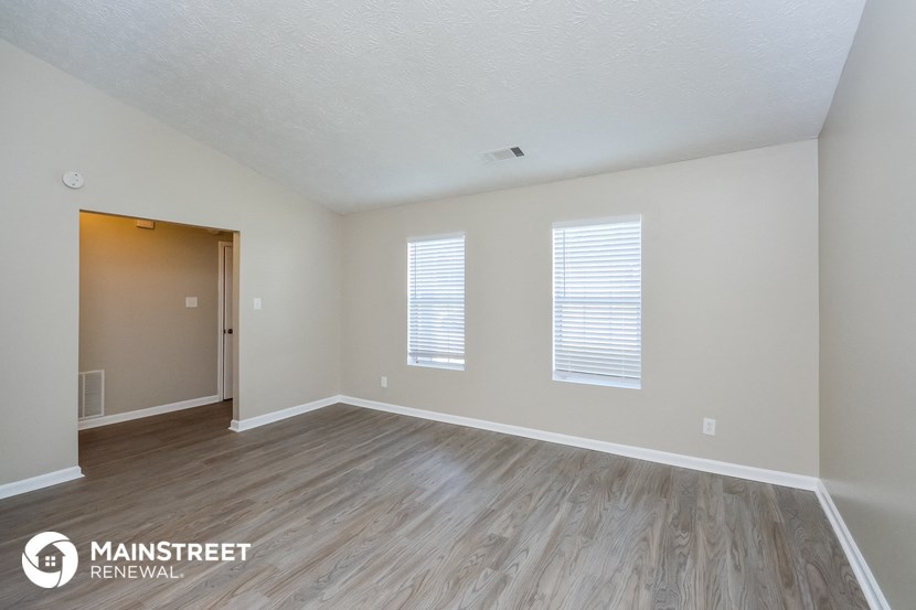 the spacious living room with wood flooring and white walls