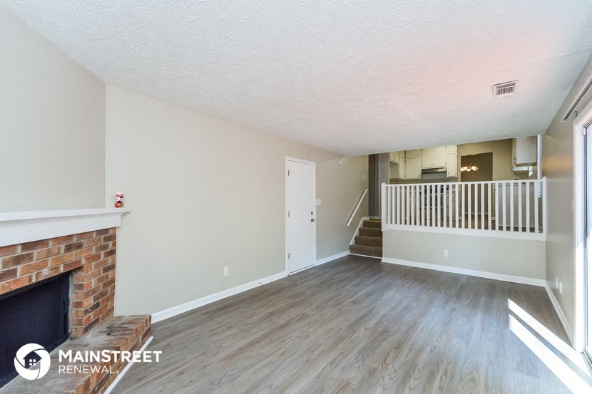 the living room of an apartment with a fireplace and wooden floors