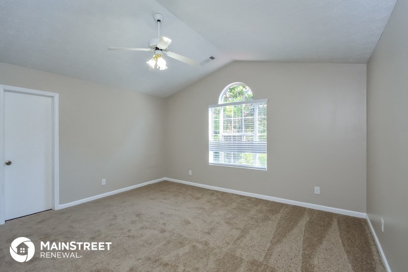 the spacious bedroom with carpeted floors and a ceiling fan