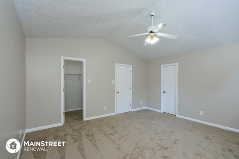 the spacious living room with carpet and a ceiling fan